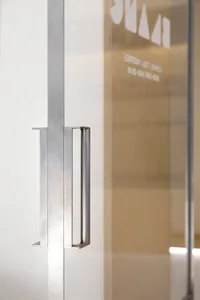 A modern interior space with a steel artwork mounted on a wall in front of a glass door, creating a sense of transparency and openness