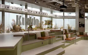 A modern interior design showroom with a glass wall, benches, and potted plants, creating a relaxing and inviting atmosphere