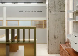 Professional office space with a concrete wall, wooden desk, and a window, featuring a sign encouraging employees to take breaks