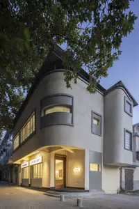 A modern building with white walls and grey trim, featuring multiple windows in various sizes and positions across its facade, creating a sense of depth and complexity in a contemporary urban environment