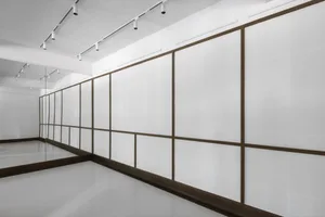 空曠白色空間配木質線條與懸吊燈具，營造乾淨極簡氛圍