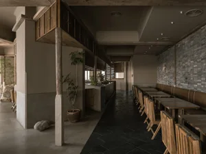 Warm and inviting restaurant interior with wooden tables and chairs, potted plants, and a cozy atmosphere