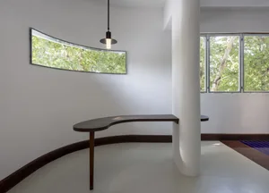 Clean and minimalistic interior space with a central column, white walls, and natural light from two windows