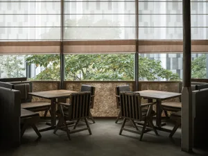 Dining area with wooden tables and chairs, large windows, and natural light