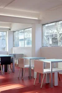 Modern restaurant interior with white walls, dining tables, and chairs, creating a clean and contemporary atmosphere