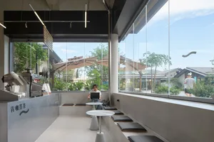 Comfortable living and dining space with multiple seating areas, tables, and a person using a laptop