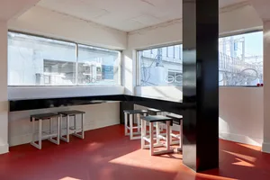 A clean and inviting restaurant interior with a long dining table surrounded by multiple wooden chairs, ready for guests to dine