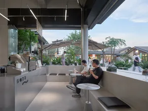 A well-lit indoor space with people sitting on benches and chairs, surrounded by a relaxed and comfortable atmosphere