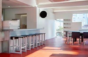 A bright and inviting restaurant interior with multiple dining tables and chairs, surrounded by sunlight and clean lines