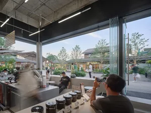A bustling restaurant and store with a mix of wood and metal elements, potted plants, and natural lighting
