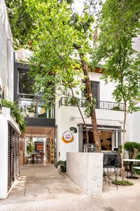 Modern living space with clean lines, minimalistic design, and a variety of furniture, including chairs, tables, and potted plants, with a lived-in atmosphere and natural light