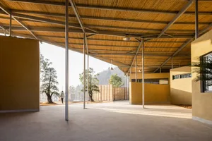 Open interior space with a large wooden structure, people walking around, and a rustic atmosphere