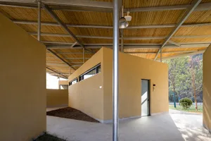 A modern building with a concrete structure, featuring yellow and brown tones, and two doors on either side, set against a perspective view