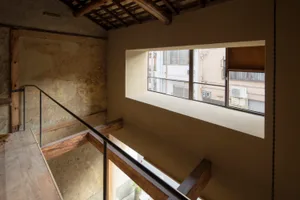 A historic building with a wooden staircase, natural light, and old architecture