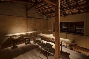 Cozy dining space with a wooden beam, stone wall, and a dining table surrounded by chairs