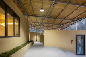 A long hallway with concrete walls and two doors, one near the left side and one further down on the right side, suggesting a functional and utilitarian design