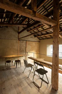 Open living space with wooden beams on the ceiling and walls, featuring a dining table and two chairs in a warm and inviting atmosphere
