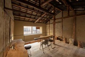 A warm and inviting living area with wooden floors and walls, featuring a kitchen, dining room, and living room with comfortable seating and decorative elements