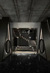 A hotel staircase with metal stairs, illuminated by lights on both sides, creating a sense of elegance and sophistication
