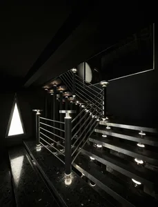 A black and white photo of a sleek metal staircase with a mirror on one side, creating a sense of depth and sophistication