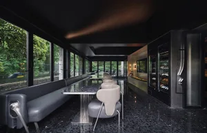 A modern restaurant interior with a large glass dining table surrounded by multiple chairs in a sophisticated and inviting atmosphere