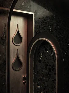 Ornate wooden doors with carved designs and water drops, set in a traditional architectural style building