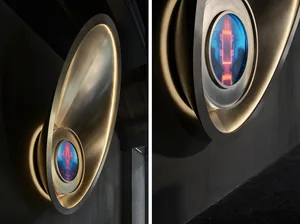 An artistic installation featuring a circular metal object with a red glow emanating from its center, viewed from above and below