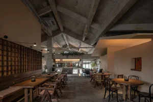 Open restaurant interior with multiple tables, chairs, potted plants, and tiled flooring contributing to a modern design