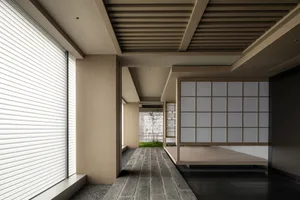 Asian-style living area with wooden floors and walls, featuring a bed in one room and a dining table in the other, with a calm and inviting atmosphere