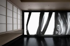 Two black and white paintings on a wall in a darkened room create a dramatic and thought-provoking atmosphere