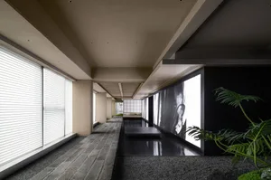 A calm and quiet hallway with a tiled floor, a large picture on one wall, and two potted plants adding greenery