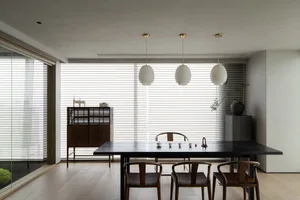 Open modern living space with a dining table, wooden chairs, and a couch, featuring a modern and inviting atmosphere