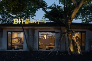 A modern Asian restaurant with large windows, dining tables, and chairs, creating a cozy atmosphere