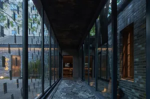A calm and inviting hallway with a stone floor, natural light, and two chairs, surrounded by walls and windows