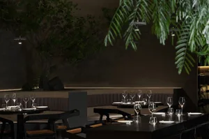 Modern restaurant interior with wood and stone elements, tables, chairs, and wine glasses, elegant and sophisticated atmosphere