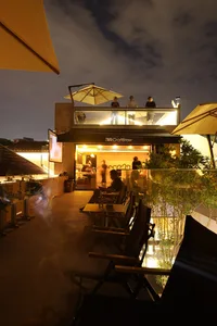 Rooftop dining area with tables, chairs, and umbrellas, offering a lively atmosphere and city views