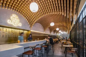 A casual restaurant interior with wooden walls and ceiling, featuring multiple tables and chairs for guests to relax and socialize