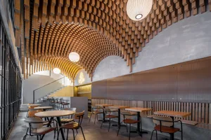 Warm and inviting restaurant interior with wooden walls and ceiling, featuring dining tables and chairs, and wine glasses on some tables