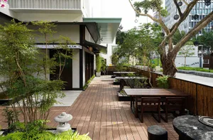 Outdoor dining area with wooden tables and chairs, surrounded by a pleasant atmosphere