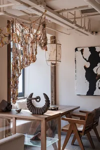 A cozy dining room with a wooden table and chairs, surrounded by books and decorative items