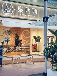 A restaurant interior with cushioned chairs, potted plants, and umbrellas, creating a welcoming atmosphere for customers