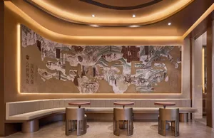 A restaurant interior with a large wall painting of a map featuring people, horses, trees, and buildings, surrounded by chairs and two dining tables, giving off a warm and inviting atmosphere