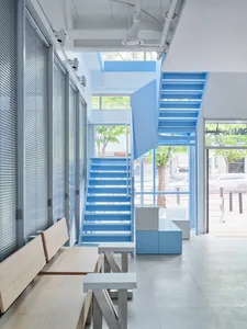 Open living area with a staircase, wooden stairs, and a bench, illuminated by natural light