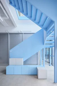 A well-lit interior space with a staircase made of wood, surrounded by a modern building's interior