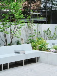 A well-designed outdoor seating area with a white bench, small table, and potted plants, set against a rendered background