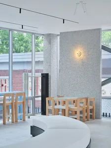 Open living area with chairs and a dining table, surrounded by natural light from a large window