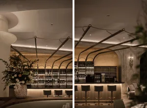 Modern bar area with gold accents, bottles, and wine glasses on countertops