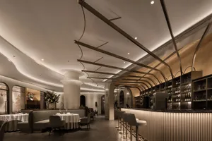 Sophisticated restaurant interior with a bar area, chairs, tables, and wine glasses, creating an inviting atmosphere