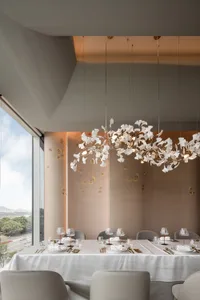 Dining area with a large wooden table surrounded by chairs, wine glasses, and cups, set in a sophisticated and inviting atmosphere