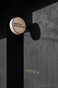 A simple sign reading Enoteca mounted on a black surface, with no surrounding details visible